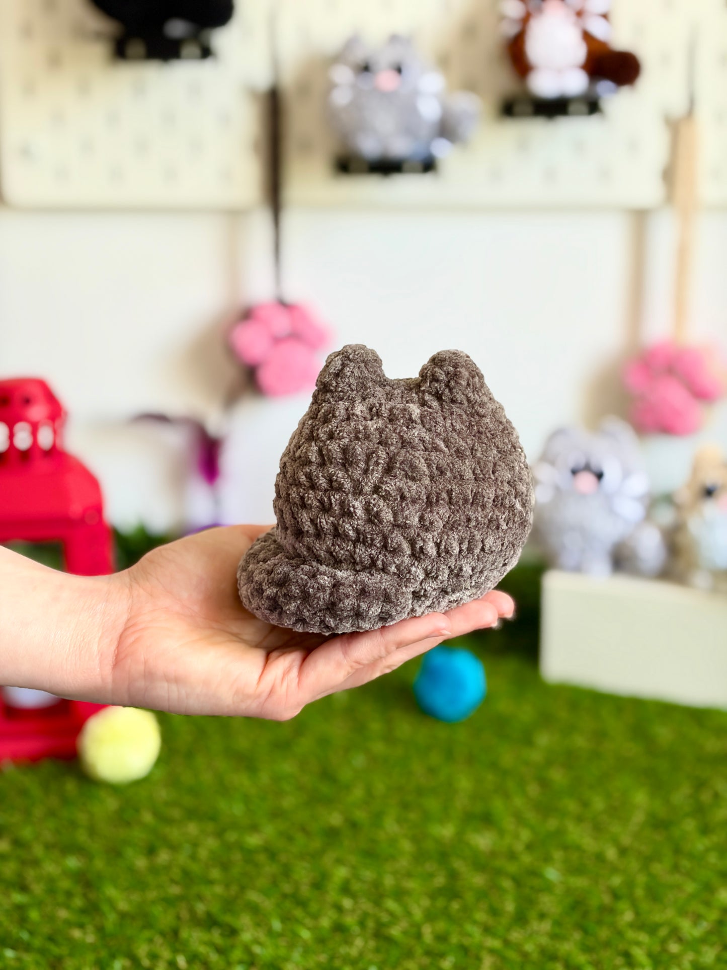 Chat flouf Nuiba, grand modèle, assis et souriant, en peluche douce avec des couleurs pastel, pour décoration ou câlins.